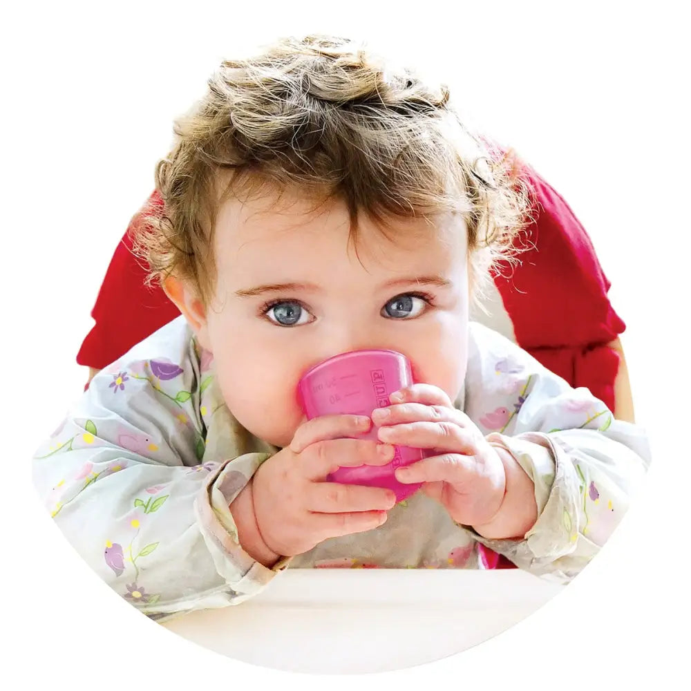 Bebé bebiendo agua de un vaso Babycup rosa